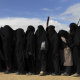 Foreign ISIS wives and children line up near the foreign section of Al Hawl camp to be taken to the shops.