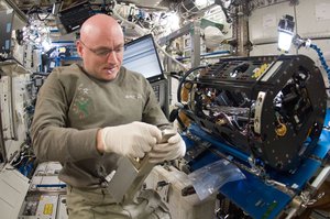 NASA astronaut Scott Kelly works on the Combustion Integrated Rack in the Destiny laboratory. A typical day for the crew begins with a wake-up at 06:00, followed by post-sleep activities and a morning inspection of the station