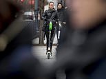 In this Dec. 4, 2018, photo a couple rides scooters near the White House in Washington. Electric scooters are overtaking station-based bicycles as the most popular form of shared transportation outside transit and cars. (AP Photo/Andrew Harnik)