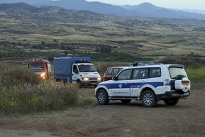 A police truck, rear left, carrying a body where found after Cypriot investigators and police officers search at a field outside of Orounta village, near the capital Nicosia, Cyprus, Thursday, April 25, 2019. Police in Cyprus confronted the possibility that a serial killer had been at large in their midst after an army captain in custody for the deaths of two women claimed responsibility for more slayings, seven in all.(AP Photo)