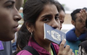 A Venezuelan migrant holds her passport while wait in line to take a bus to continue their travel in Tumbes, Peru, Saturday, Aug. 25, 2018.