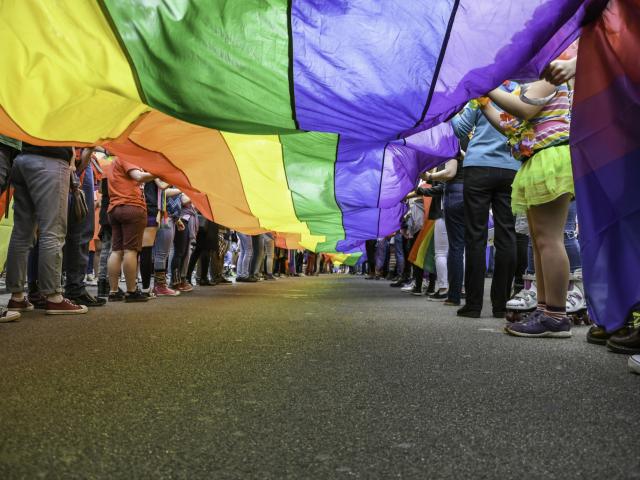 People holding LGBTQ flag