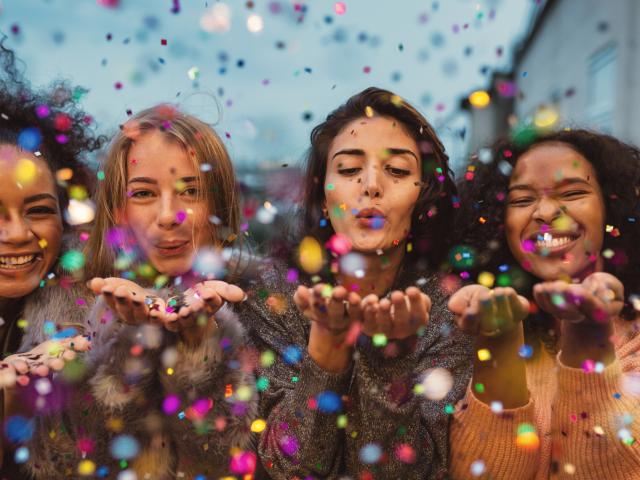 Young women blowing confetti from hands