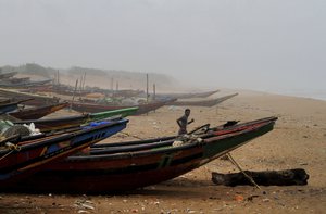 An Indian fisherman runs between the docked fishing boats amid strong winds at Chandrabhaga beach in Puri district of eastern Odisha state, India, Thursday, May 2, 2019.