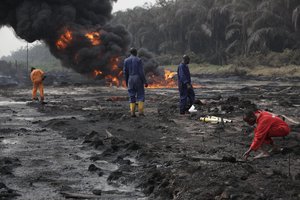 Fire fighters try to contain flames and a tower of smoke from a burning oil pipeline in Ijeododo outskirt of Lagos, Nigeria Thursday, Dec. 20, 2012.