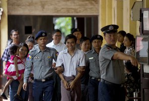 Reuters journalists Kyaw Soe Oo, centre front, and Wa Lone, center back, are escorted by police upon arrival at their trial Monday, July. 30, 2018, Yangon, Myanmar.