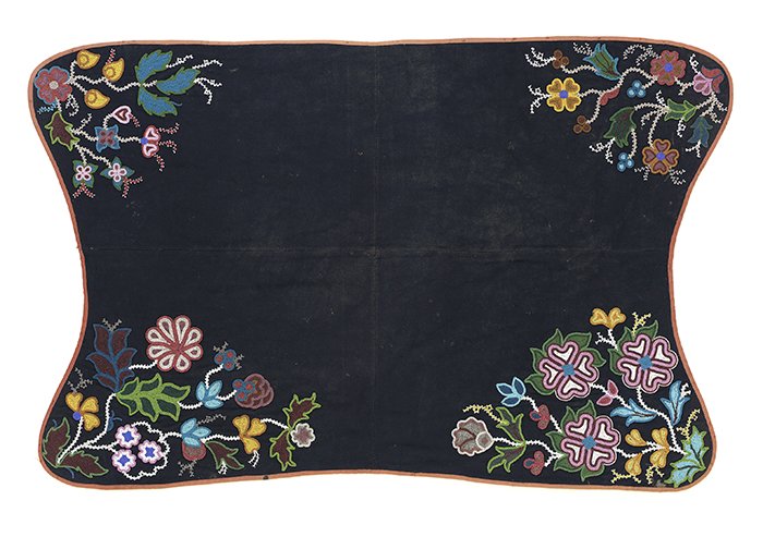 A dark blue black in a rectangular shape with curved sides. It has an orange border. Each corner has a floral embroidered design in bright blues, yellows and pinks.