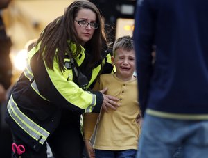 Officials guide students off a bus and into a recreation center where they were reunited with their parents after a shooting at a suburban Denver middle school Tuesday, May 7, 2019, in Highlands Ranch, Colo.