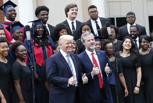 President Donald Trump poses with Liberty University president, Jerry Falwell Jr., center right, in front of a choir during of commencement ceremonies at the school in Lynchburg, Va., Saturday, May 13, 2017.