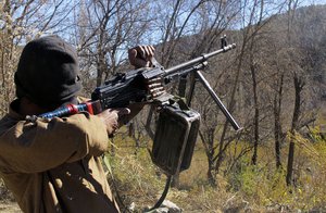 In this Sunday, Dec. 11, 2011 photo, a masked Pakistani Taliban militant fires a machine gun during a training session in an area of Pakistan's tribal South Waziristan region along the Afghan border.