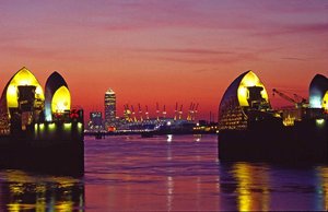 File - The Thames Barrier at Dusk with Canary Wharf and Millennium Dome in the background. The barrier stops the floodplain of most of Greater London from being flooded by exceptionally high tides and storm surges moving up from the North Sea.