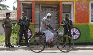 FILE - In this Monday, May 6, 2019 file photo, a Sri Lankan Muslim rides past soldiers securing a Muslim neighborhood following overnight clashes in Poruthota, a village in Negombo, about 35 kilometers North of Colombo, Sri Lanka.