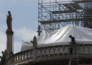 A worker checks the waterproof tarps on Notre Dame cathedral in Paris, Friday, April 26, 2019.