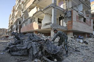 An Iranian army soldier inspects a smashed car by the debris of an earthquake damaged building, in a compound which was built under the Mehr state-owned program, in Sarpol-e-Zahab in western Iran, Wednesday, Nov. 15, 2017.