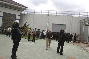 Police officers armed with tear gas launchers stand guard outside Sialang Bungkuk Prison following the escape of hundreds of its inmates in Pekanbaru, Riau province, Indonesia, Friday, May 5, 2017.