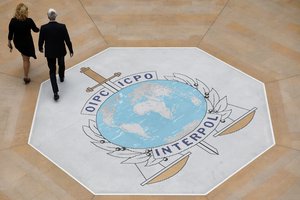 People walk on the Interpol at the international police agency logo in Lyon, central France, Thursday, Nov.8, 2018.