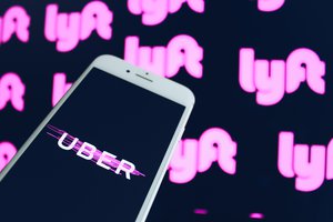 Uber app on smartphone with Lyft logos on background