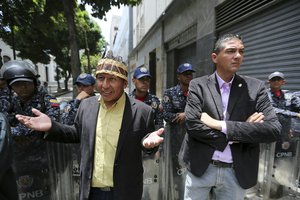 Opposition lawmakers Romel Edgardo Guzamana, left, and his collage Angel Torres, stand in front of a cordon of Venezuelan Bolivarian National Police blocking the access to congress, in Caracas, Venezuela, Tuesday, May 14, 2019