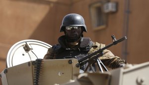 A soldier stands guard in an APC outside the Splendid Hotel that was attacked in Ouagadougou, Burkina Faso, Monday, Jan. 18, 2016.