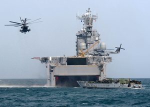 Activity hums around the USS Tarawa (LHA-1), as U.S. Marines go ashore in Kuwait. In mid October 2000, the Tarawa was passing through the Strait of Hormuz on her way into the Persian Gulf when the USS Cole was attacked.