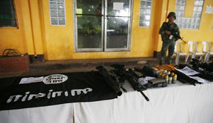 A Philippine Marine guards the display of recovered high-powered firearms, ammunitions, uniforms and black ISIS-style flags which were shown to reporters Tuesday, May 30, 2017 in Marawi city southern Philippines.