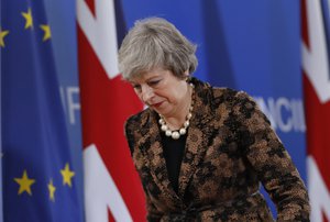 British Prime Minister Theresa May walks by the Union Flag and EU flag as she departs a media conference at an EU summit in Brussels, Friday, Dec. 14, 2018.