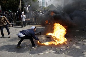 Protesters try to put out fire from a burning tyre in Jakarta, Indonesia, Wednesday, May 22, 2019