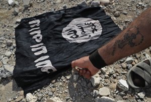 A fighter of Christian Syriac militia that battles IS under the banner of the U.S.-backed Syrian Democratic Forces, burns an Islamic State flag on the front line on the western side of Raqqa, northeast Syria, Monday, July 17, 2017.