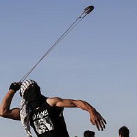 Illustrative: A Palestinian hurls stones at Israeli troops during clashes near the border with Israel, east of Gaza City, on May 10, 2019. (Said Khatib/AFP)