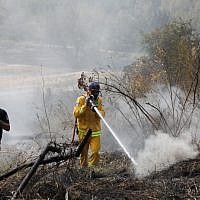 Firefighters extinguish the remains of a fire in Kibbutz Harel, on May 24, 2019. (Noam Revkin Fenton/Flash90)