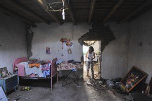 A woman observes her damaged home after an earthquake in Acari, Peru, Sunday, Jan. 14, 2018