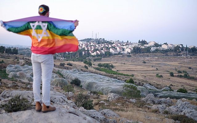 An Israeli teen wrapped in a Gay Pride flag near the settlement of Efrat, June 3, 2018. (Jacob Magid/Times of Israel)