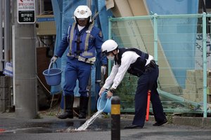 Police officers clean the scene where a man wielding a knife attacked commuters Tuesday, May 28, 2019, in Kawasaki, near Tokyo