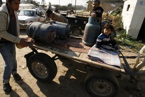 File - Palestinians fill empty gas cylinders at a gas station in the southern Gaza Strip town of Rafah. The 12-year blockade of the Gaza Strip has contributed to a worsening humanitarian crisis.