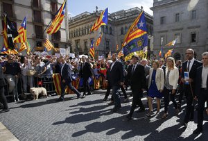 The President of the government of Catalonia, Carles Puigdemont, foreground, walks with a number of mayors under investigation, outside the Generalitat Palace, to protest against the ruling of the constitutional court ahead of a planned independence referendum in the Catalonia region, in Barcelona, Spain, Saturday, Sept. 16, 2017.