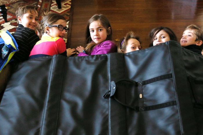 Children lying under a black bulletproof blanket