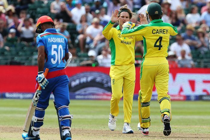 Alex Zampa double hi-fives his teammate after dismissing Hashmatullah Shahid, who trudges off back to the pavillion