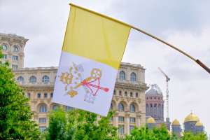 Flag of Vatican City on display in front of the Palace of Parliament in Bucharest, during Pope Francis 2019 visit in Romania. Via Shutterstock