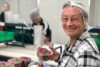 Kathy Black holding two punnets of strawberries with a hair net on in a packing area.