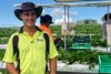 Worker Ashley Barnes standing with strawberries with people picking strawberries behind him.