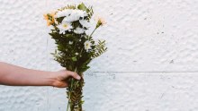 Person holding a bunch of white and peach-coloured flowers for a story about apologising for past bullying and bad behaviour.