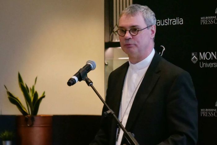 Melbourne Archbishop Peter Comensoli standing at a lectern and microphone.