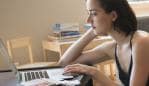 Caucasian mother sitting on floor using laptop near baby son