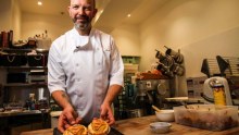 A baker holds cooked pies in his hands