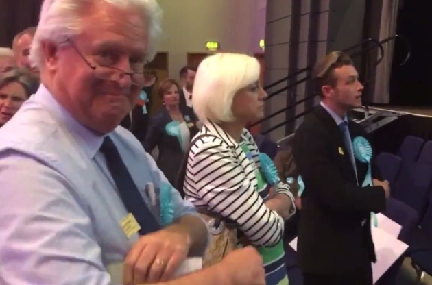 A Brexit Party supporter grins at the camera as others heckle Labour MEP Neena Gill during her acceptance speech. Picture: Twitter/supplied