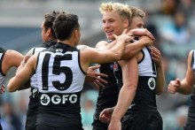 Port Adelaide players hug and congratulate a smiling Billy Frampton.