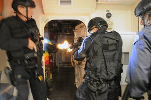 File - Los Angeles Special Weapons and Tactics (SWAT) team members breach a room and engage hostile targets in a training exercise focusing on breach and clear tactics aboard maritime vessels, San Diego, California.