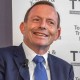 Tony Abbott smiles as Zali Steggall speaks into a microphone at the Warringah candidates' forum.