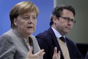 German Chancellor Angela Merkel, left, and German Transportation Minister Andreas Scheuer, right, address the media during a press conference at the chancellery in Berlin, Germany, Monday, Dec. 3, 2018 after a meeting with representatives of German cities that are affected by nitrogen oxide limit violations.