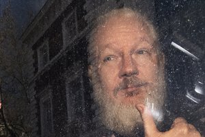 Julian Assange gestures as he arrives at Westminster Magistrates' Court in London, after the WikiLeaks founder was arrested by officers from the Metropolitan Police and taken into custody Thursday April 11, 2019.